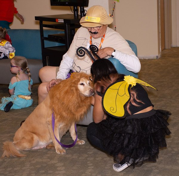 girl dressed as bee pets dog